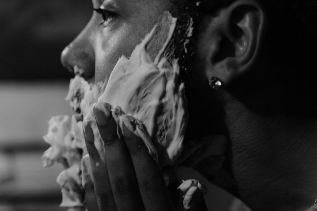 Black and white photo of a man applying shaving cream with a focused expression.